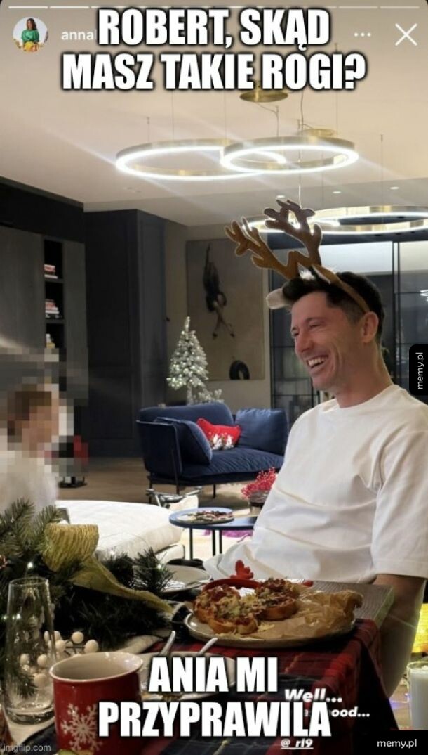 Robert Lewandowski w rogach renifera siedzi przy stole w salonie.