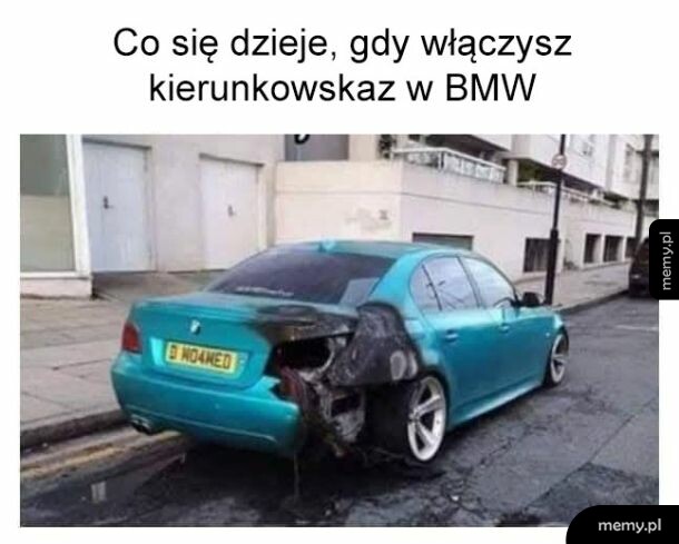 Niebieskie BMW z mocno uszkodzonym i przypalonym tyłem zaparkowane na ulicy.