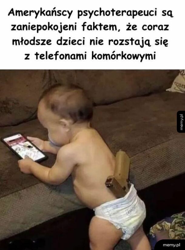 Małe dziecko w pampersie przegląda telefon, mając pistolet włożony za pieluchę.